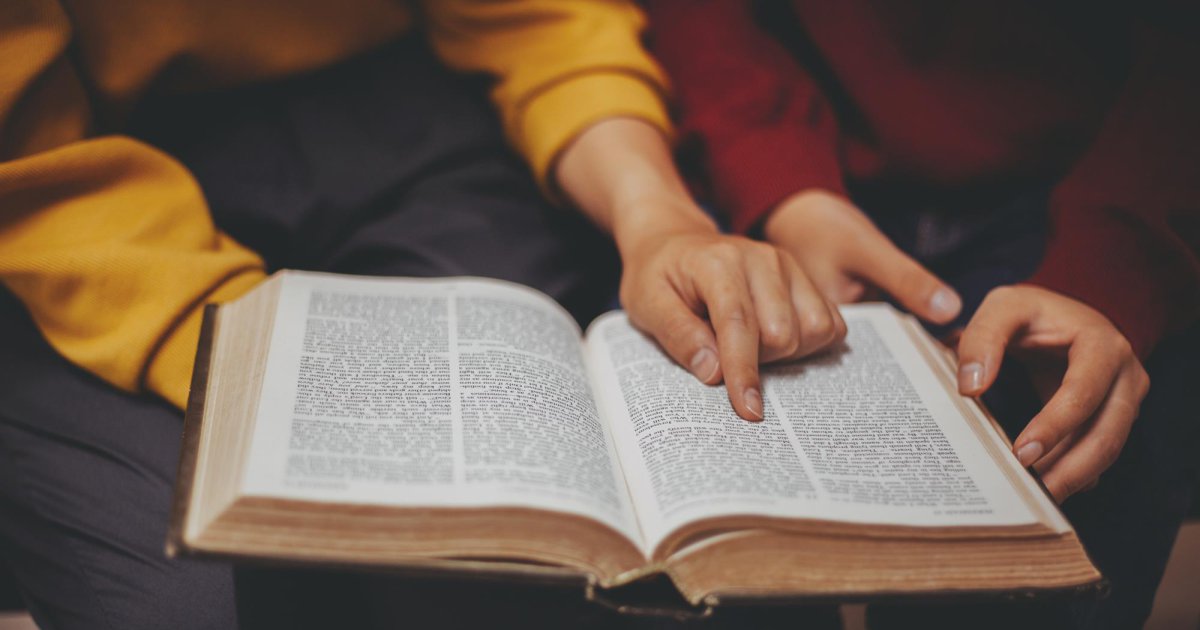 Handen op een opengeslagen Bijbel tijdens de catechisatie